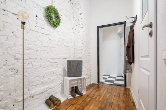 Industrial style mudroom with white brick wall and rustic hardwood flooring